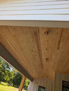 Wooden plank ceiling on a covered porch.