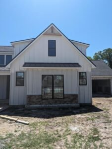 Newly constructed farmhouse-style home with white siding, black accents, and a welcoming front porch.
