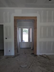 Interior construction progress, featuring a custom wood beam accentuating the entryway and a built-in shelving unit.