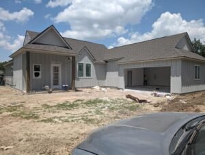 Gray house with white doors under construction by WTH Construction