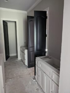 Bathroom renovation in progress in Lafayette, LA by WTH Construction, featuring double vanities and black doors.