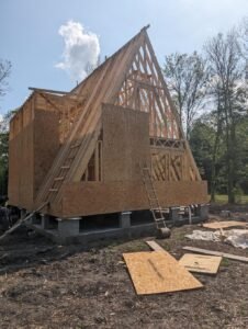 A-frame house under construction with exposed wooden frame.